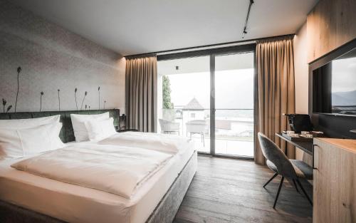 a bedroom with a large bed and a television at SomVita Suites in Tirolo
