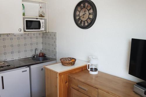 a kitchen with a sink and a clock on the wall at Charmant studio refait à neuf in La Foux