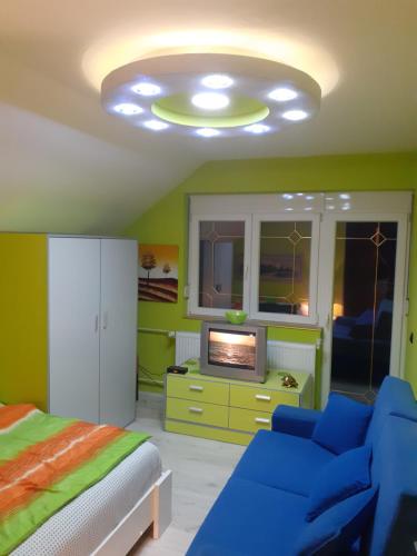 1 dormitorio con sofá, cama y TV en Vidikovac Dedinje, en Šabac