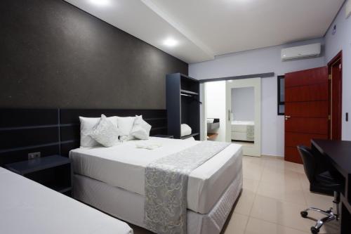 ein Schlafzimmer mit einem weißen Bett und einer schwarzen Wand in der Unterkunft Sophita Business Hotel in Itaberá
