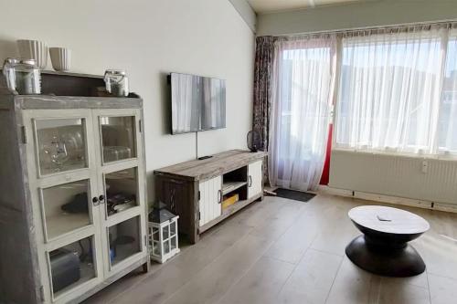 a living room with a tv and a stool in it at Beach Appartement 17 - Aan de duinen, Callantsoog aan Zee in Callantsoog