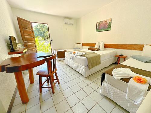 a hotel room with two beds and a table at Eco Pousada Paraíso dos Coqueirais in Japaratinga