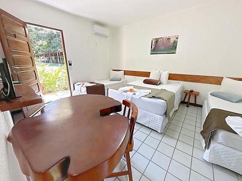 a room with a table and a bed and a couch at Eco Pousada Paraíso dos Coqueirais in Japaratinga