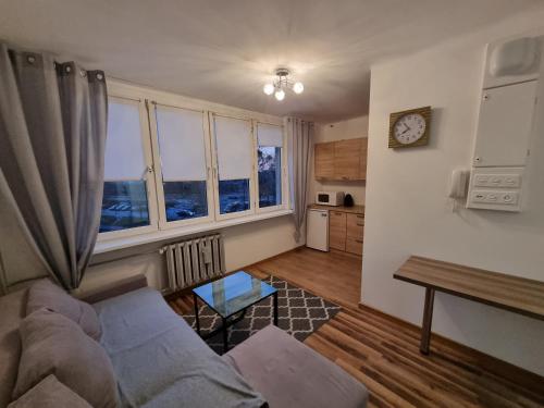 ein Wohnzimmer mit einem Sofa und 2 Fenstern in der Unterkunft Apartament 41 in Częstochowa