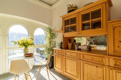 uma cozinha com armários de madeira e uma mesa com cadeiras em Edelweiss Schlosswohnung em Flims