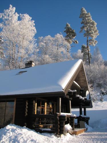 a log cabin with snow on the roof at Nuustaku Guesthouse in Otepää