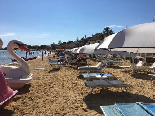 a beach with chairs and umbrellas and a swan on it at Villa Maresa Home in Realmonte