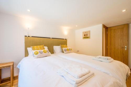 a bedroom with a large white bed with towels on it at Pinetum Garden Cottages in St Austell