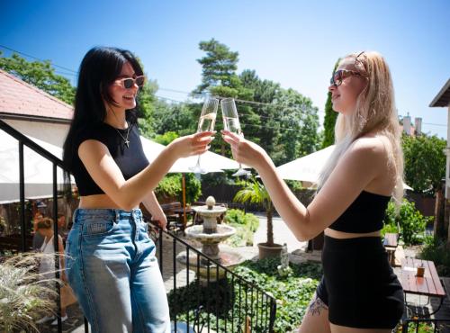 two women holding glasses of wine in a garden at Penzión Wellness & Restaurant Zoborská, free parking in Nitra