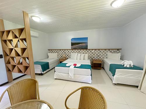 a bedroom with two beds and chairs in a room at Eco Pousada Paraíso dos Coqueirais in Japaratinga