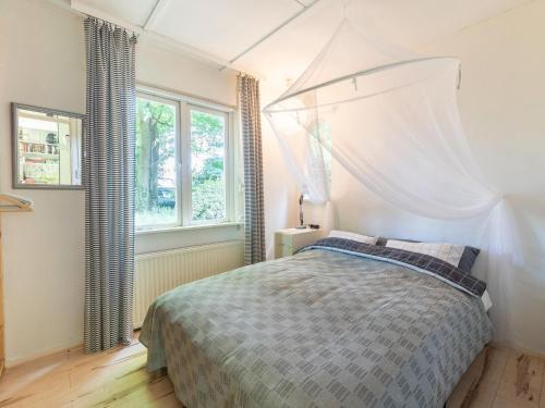 1 dormitorio con 1 cama con dosel y 2 ventanas en Tranquil holiday home in Epse with sauna, en Epse