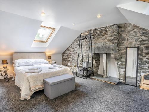 - une chambre dotée d'un mur en pierre avec un lit et une cheminée dans l'établissement The Forge, à Llanfair Clydogau