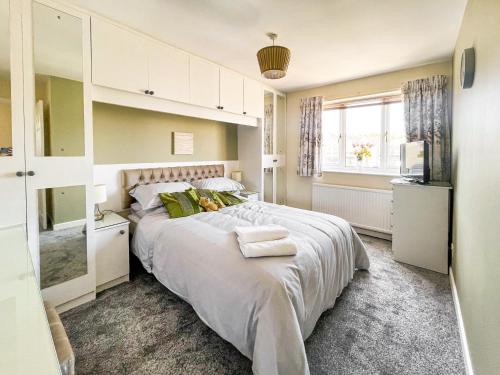 a bedroom with a large white bed with green pillows at Buxton Holiday Home in Buxton
