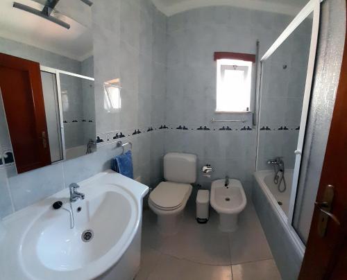 a white bathroom with a sink and a toilet at Apartamento Oliveira in Vila Real de Santo António
