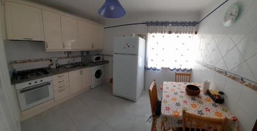 a kitchen with a table and a white refrigerator at Apartamento Oliveira in Vila Real de Santo António
