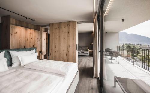 a bedroom with a white bed and a balcony at SomVita Suites in Tirolo