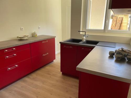 una cocina con armarios rojos y fregadero en Maison 5 chambres 3sdb en ville avec piscine, en Périgueux