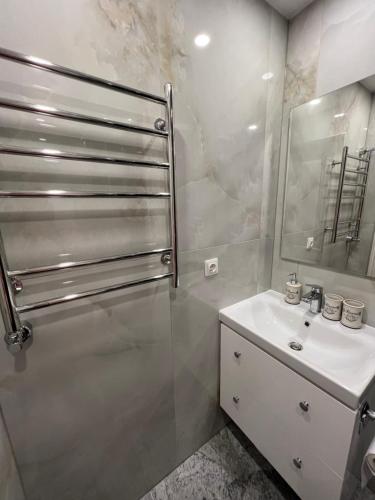 a bathroom with a sink and a shower with a mirror at Stradinya apartment in Ventspils
