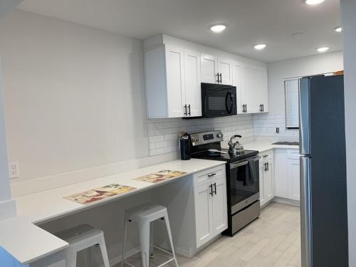 uma cozinha com armários brancos e um frigorífico preto em Beach Front Apartment Overlooking the Gulf em Clearwater Beach