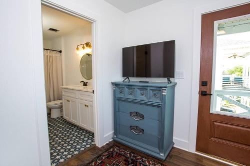 a bathroom with a blue dresser with a television on it at La Casa Boheme in Pensacola