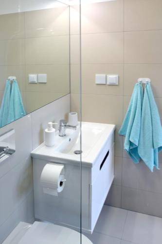 a white bathroom with a sink and a mirror at Bursztynek in Stegna