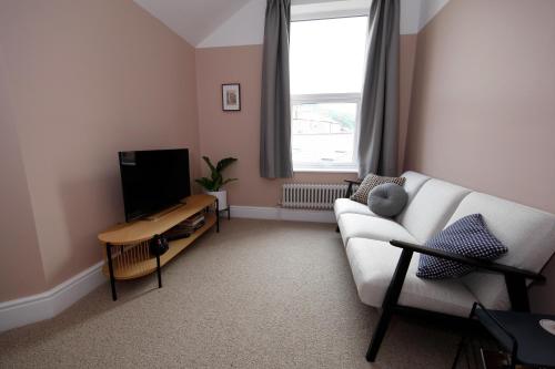 a living room with a white couch and a television at The Artist's House in Scarborough