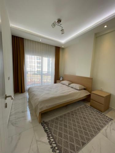 a bedroom with a bed and a window and a rug at Calypso Residence Kestel in Alanya