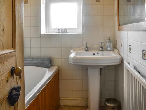 a bathroom with a sink and a bath tub at Flint House in Sheringham