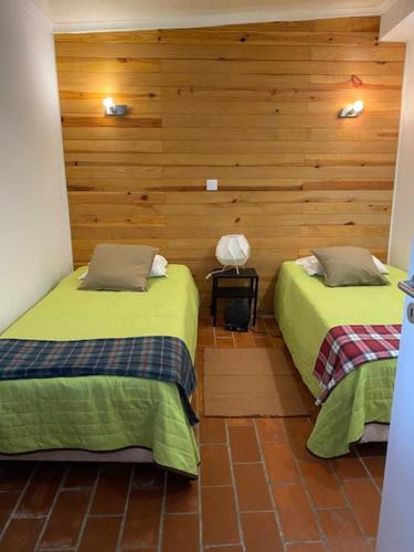 een slaapkamer met 2 bedden en een houten muur bij The Tiles House in Faro