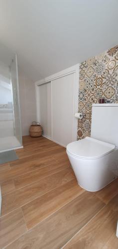 a bathroom with a white toilet and a wooden floor at Atico en apartamentos O Grove centro in O Grove