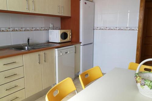 a kitchen with a table and chairs and a microwave at Apartamento primera linea de Playa. Wifi in Retamar