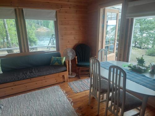 uma sala de estar com um sofá, uma mesa e cadeiras em Lakeside Lea, rantamökki 