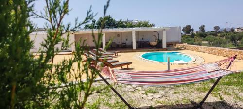 - un hamac en face d'une maison avec piscine dans l'établissement Grey Haven Luxury Villa, à Stérnai