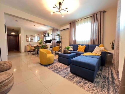 un soggiorno con divano blu e sedie gialle di Modern luxurious apartment a Santiago de los Caballeros