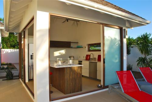 an outdoor kitchen with sliding glass doors and red chairs at Zenith Nevis in Nevis