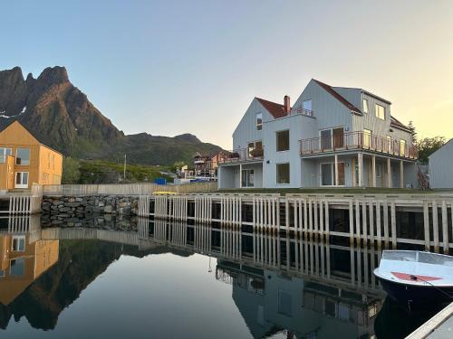 una casa y un barco en un cuerpo de agua en The Modern Fisherman Cabin Lofoten, en Ballstad