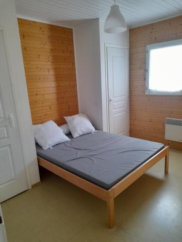 Cama en habitación con pared de madera en Camping Municipal L'Espazo DURBAN CORBIERES, en Durban-Corbières