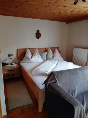 een bed met witte kussens en een tafel in een kamer bij Haus Antonius in Sankt Lorenzen im Lesachtal