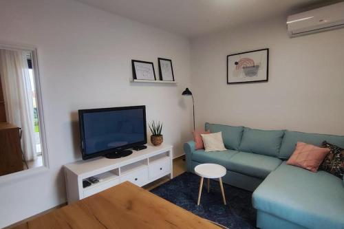 a living room with a blue couch and a tv at Salona Garden Apartman in Solin