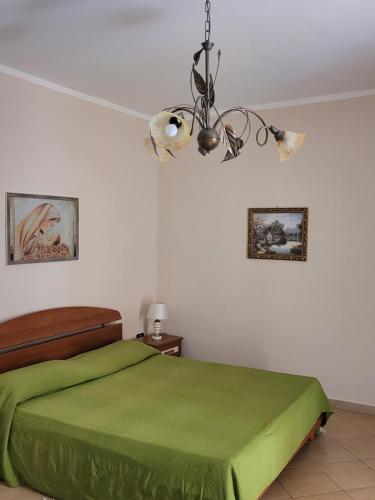 Un dormitorio con una cama verde y una lámpara de araña. en Casa Murales, en Diamante