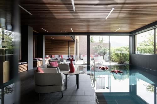 Cette chambre dispose d'une piscine, de chaises et d'une table. dans l'établissement Designhotel Gius La Residenza, à Caldaro