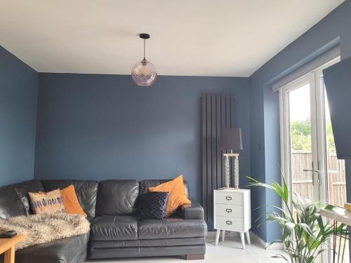 a living room with a black couch and blue walls at The Little Red House in Sheffield