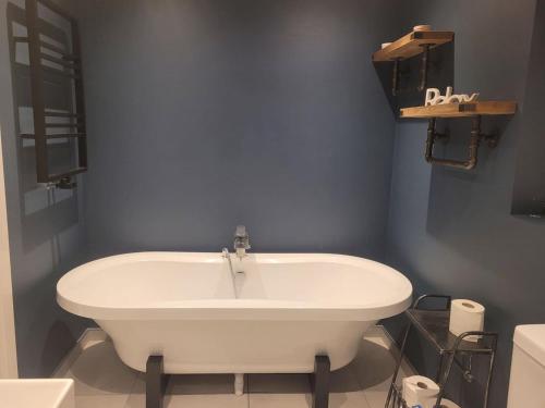 a white bath tub in a bathroom with blue walls at The Little Red House in Sheffield