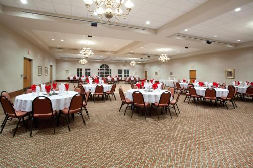 un salón de banquetes con mesas y sillas con rosas rojas. en Baymont by Wyndham Belen NM en Belen