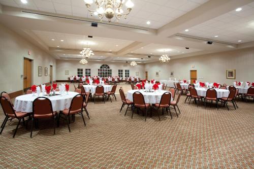 Baymont by Wyndham Belen NM في Belen: قاعة احتفالات عليها طاولات وكراسي عليها ورد احمر