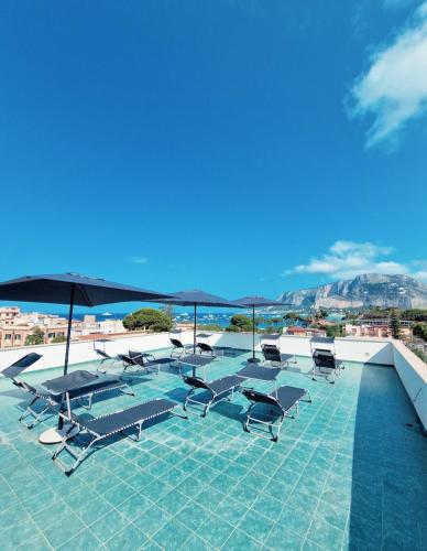 a pool with lounge chairs and umbrellas on a roof at Mongibello Palace B&B in Mondello