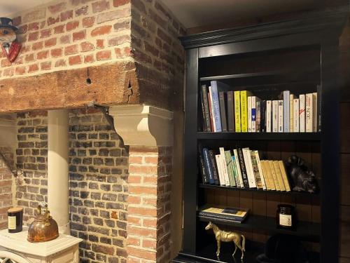 een boekenplank gevuld met boeken naast een stenen muur bij Gîte le Terrier in Hotot-en-Auge