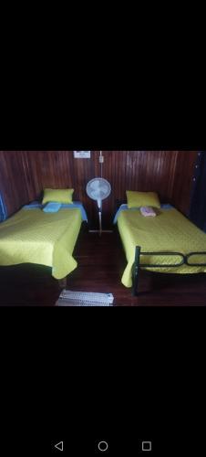 two beds with yellow sheets in a room at Atardeceres in Puntarenas