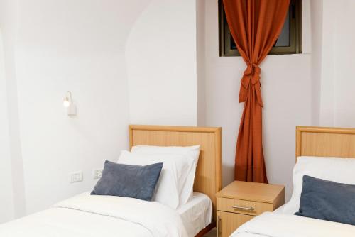 a bedroom with two beds and a window with curtains at William's Guest House in Jerusalem