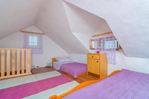 a attic room with a bed and a dresser and windows at Vacation House, PARKING INCLUDED, Lovrecina in Postira